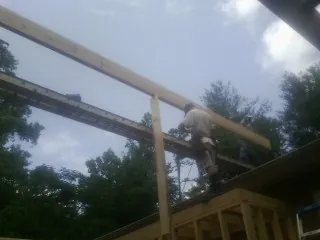 Carpenter setting a ridge beam over a new addition frame — Ice Dam Removal by Roofing Brothers in Hyattsville