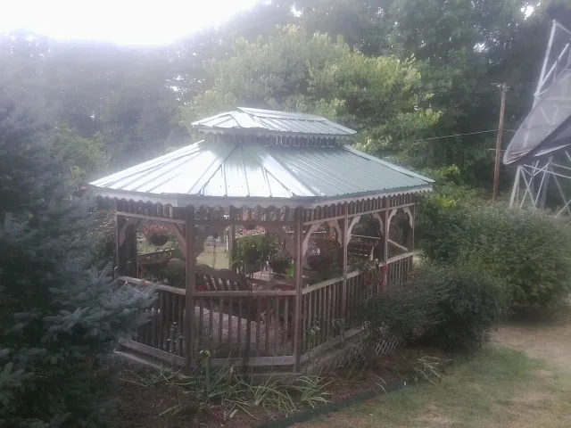Green metal roof on a backyard gazebo surrounded by garden beds in Hyattsville