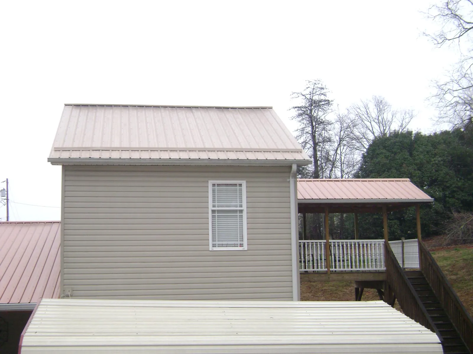 Tan metal roofs on a two story addition and attached porch, from a Roof Replacement job in Hyattsville