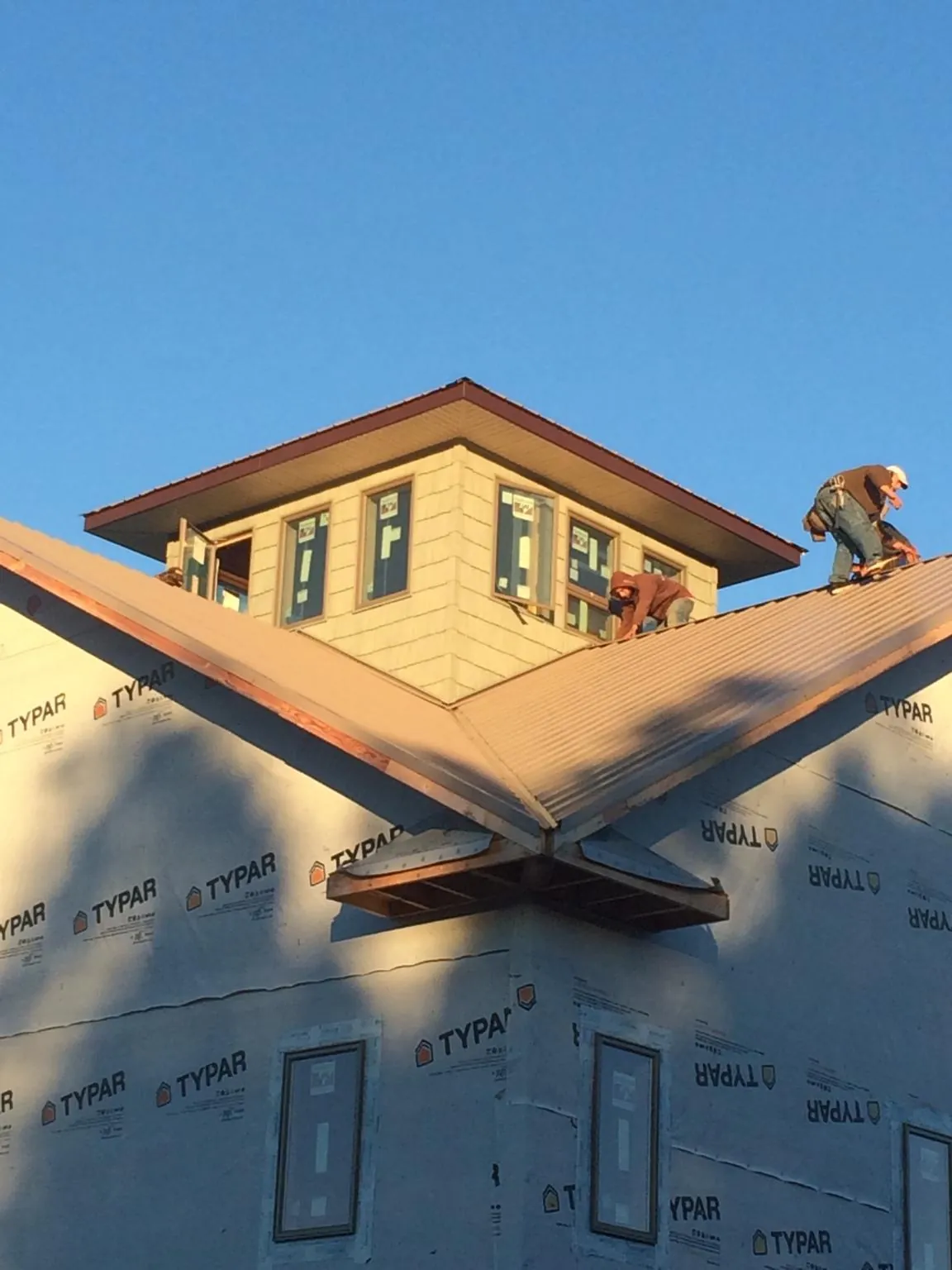 Roofers working around a rooftop cupola on a new metal roof at sunset — Roof Waterproofing in Hyattsville by Roofing Brothers